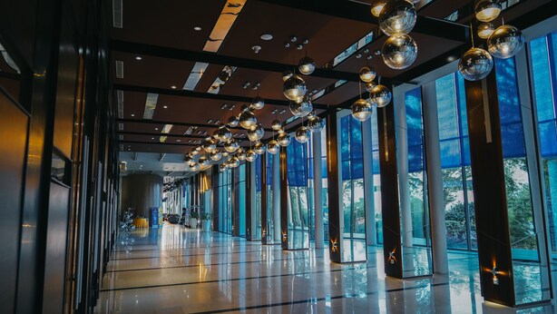 A modern hotel corridor with reflective spherical ceiling lights, large windows, and a polished floor. - Hotel Novotel Banjarmasin Airport (Banjarbaru)