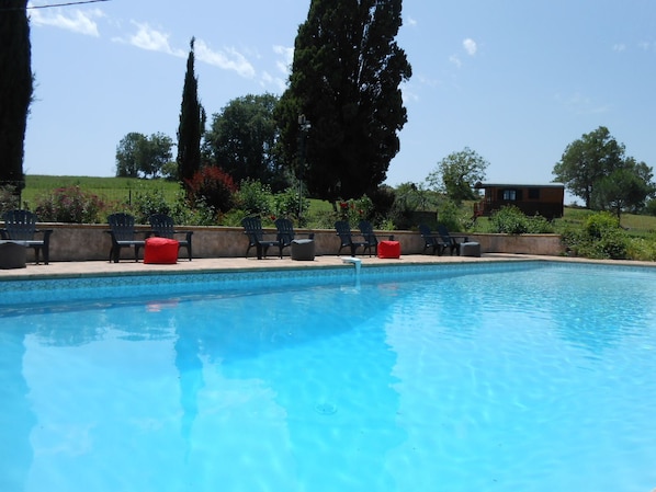 Una piscina al aire libre, sombrillas, tumbonas