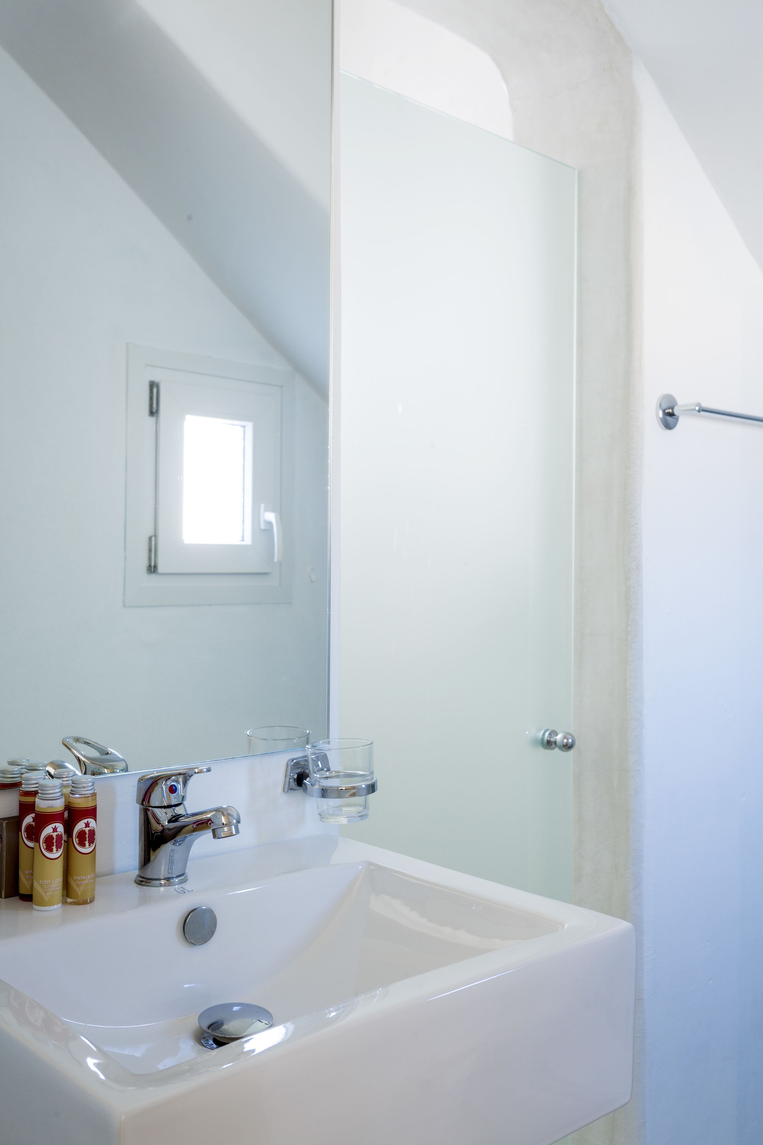 A bathroom with a large mirror, a sink, and a shower door.