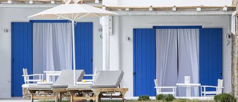 Un área junto a la piscina con sillones, una sombrilla y una mesita.