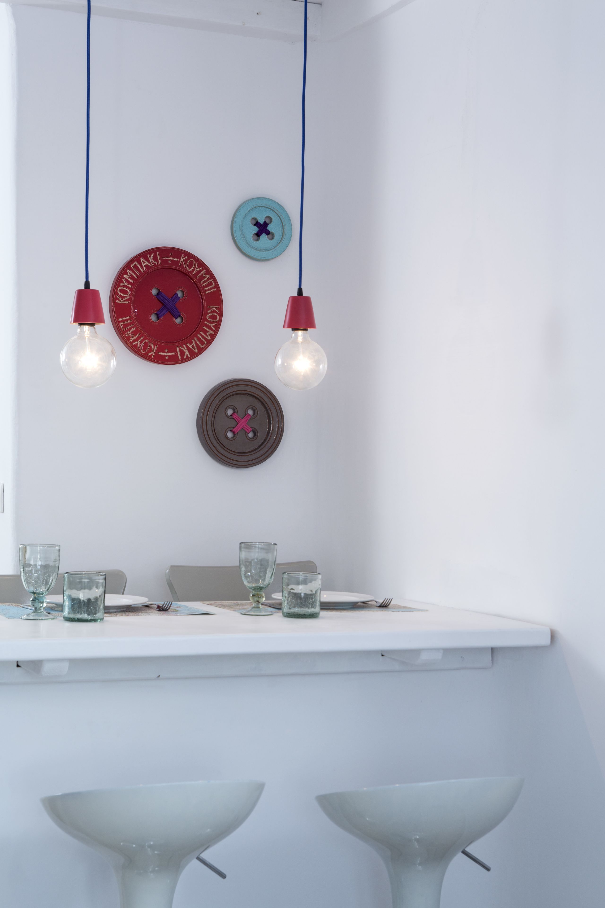 A dining area with a white table, two white chairs, and hanging light fixtures.