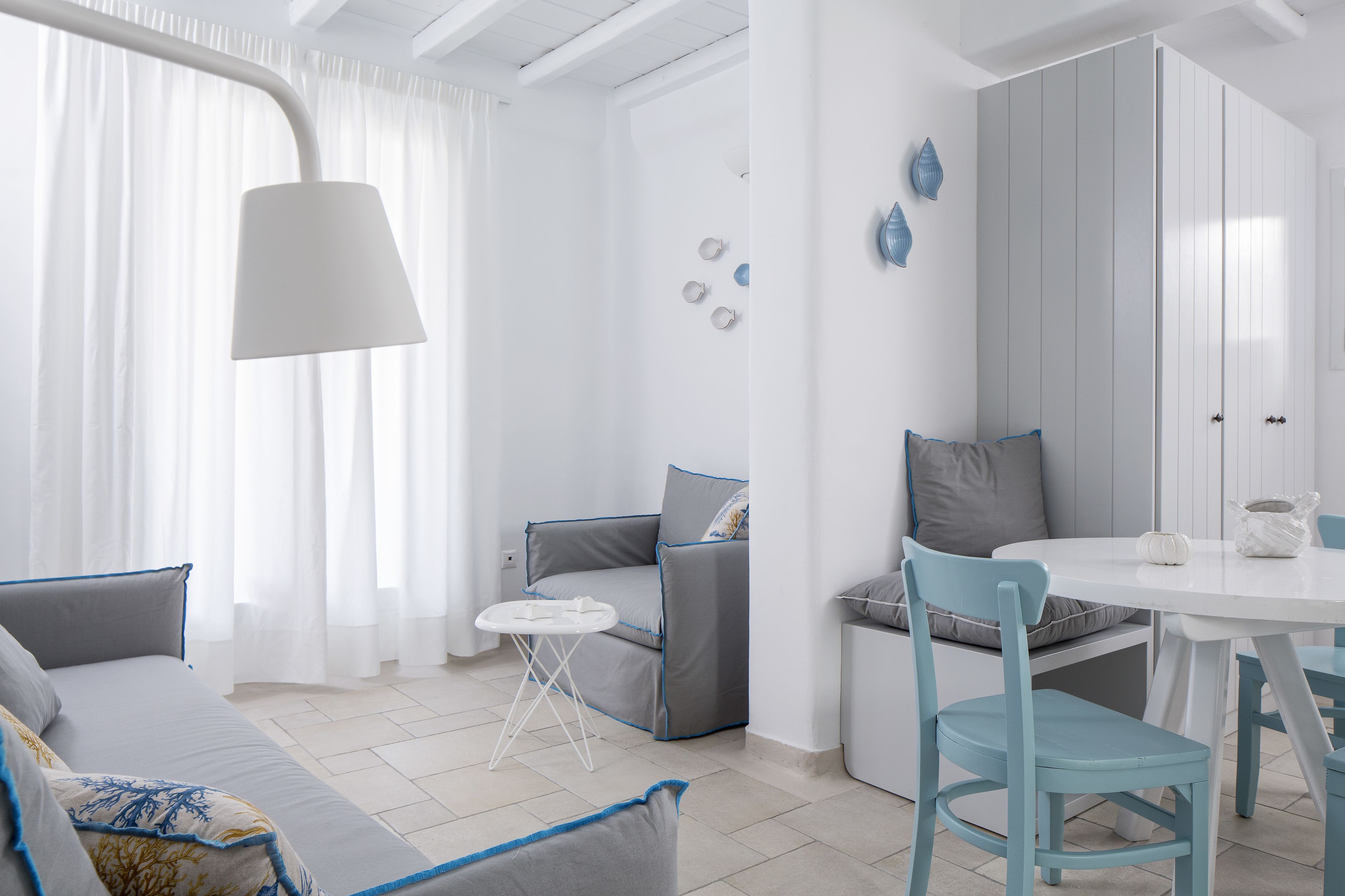 Quarto moderno e bem iluminado com sofá, mesa pequena e espaço para refeições.