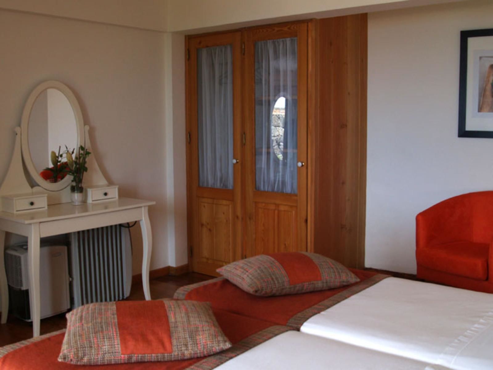 Un dormitorio con una cama, un escritorio con espejo y dos puertas.