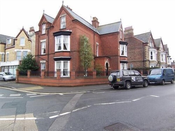A red brick house with a bay window, a front garden, and a parked car.