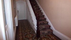 A staircase with patterned carpet and wooden steps leading to a white door. - The Hollies (Bridlington)