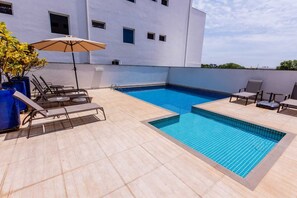 Una piscina al aire libre, sillones reclinables de piscina
