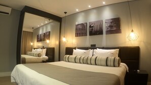 Une chambre d’hôtel moderne avec un grand lit, des tables de chevet, un miroir et des œuvres d’art accrochées au mur.