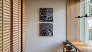 Un intérieur moderne avec une longue table et des chaises en bois, deux œuvres d’art en noir et blanc accrochées au mur, et une cloison coulissante en bois.