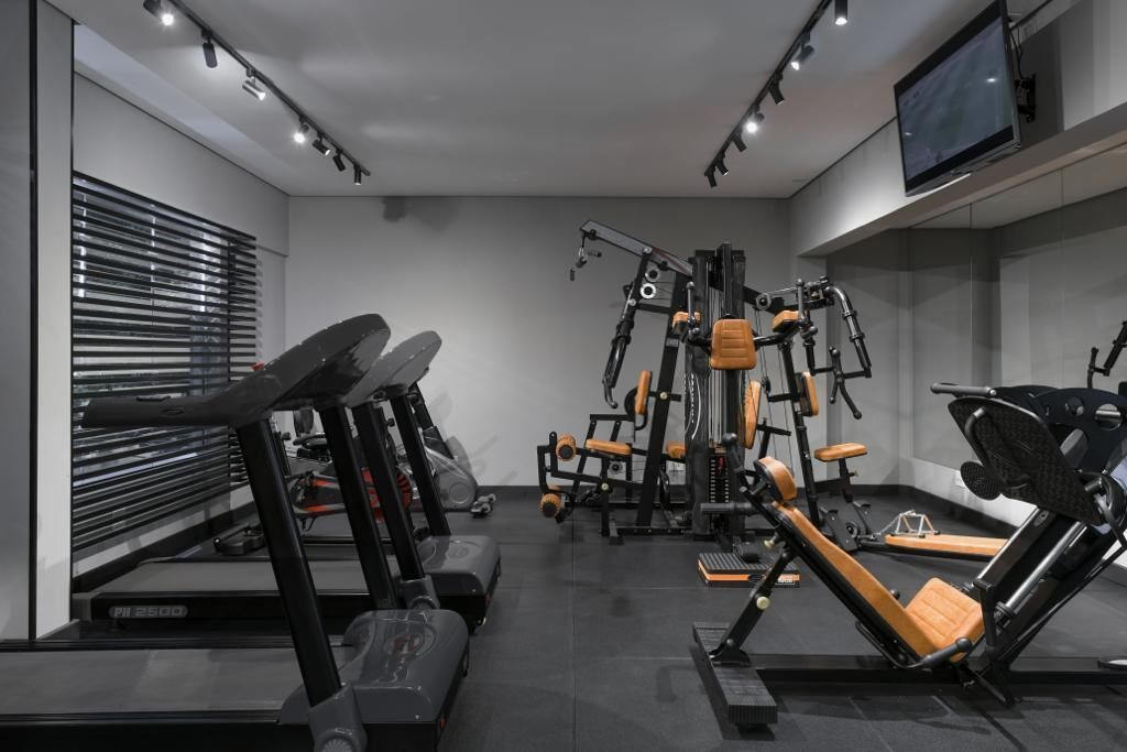 Et moderne fitnesscenter med løbebånd, styrkemaskiner og et tv monteret på væggen.