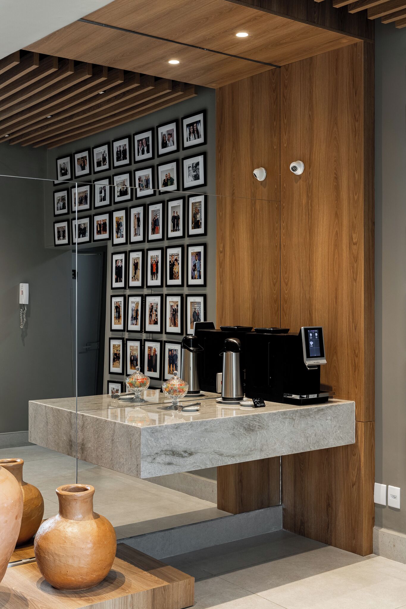 A modern reception area with a coffee machine, framed photos on the wall, and a wooden accent wall.