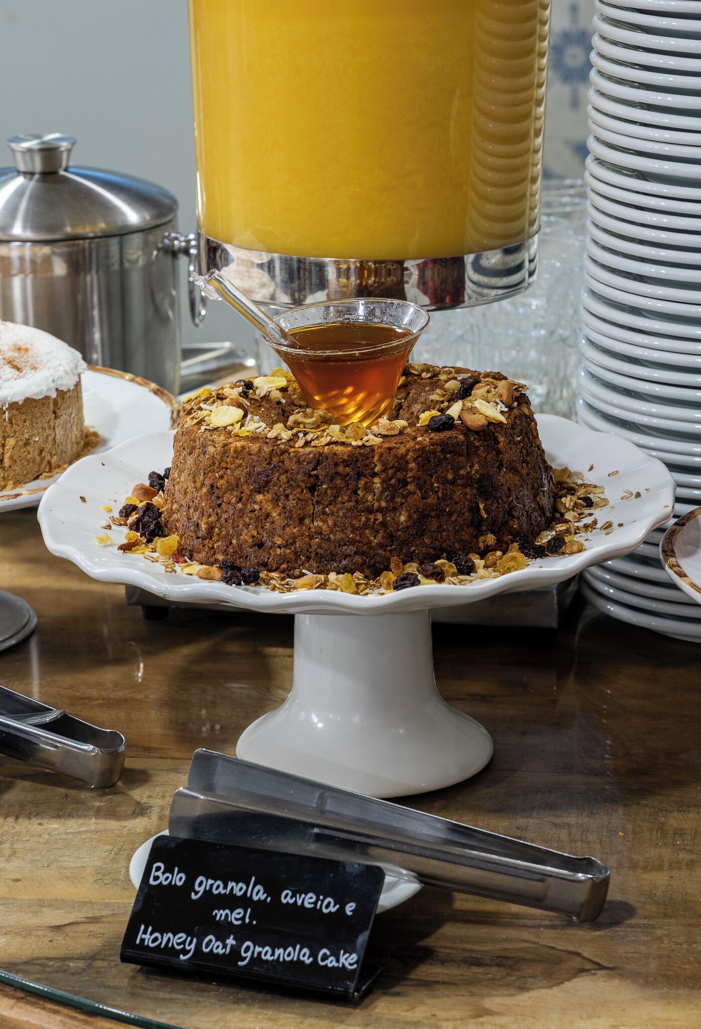 A cake with a honey glaze on a white cake stand.