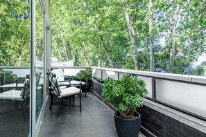 A balcony with a glass door, a table with chairs, and potted plants. - 1828 Smart Hotel (Buenos Aires)