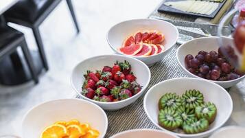 A table with bowls of sliced fruits including strawberries, oranges, grapefruit, grapes, and kiwi.