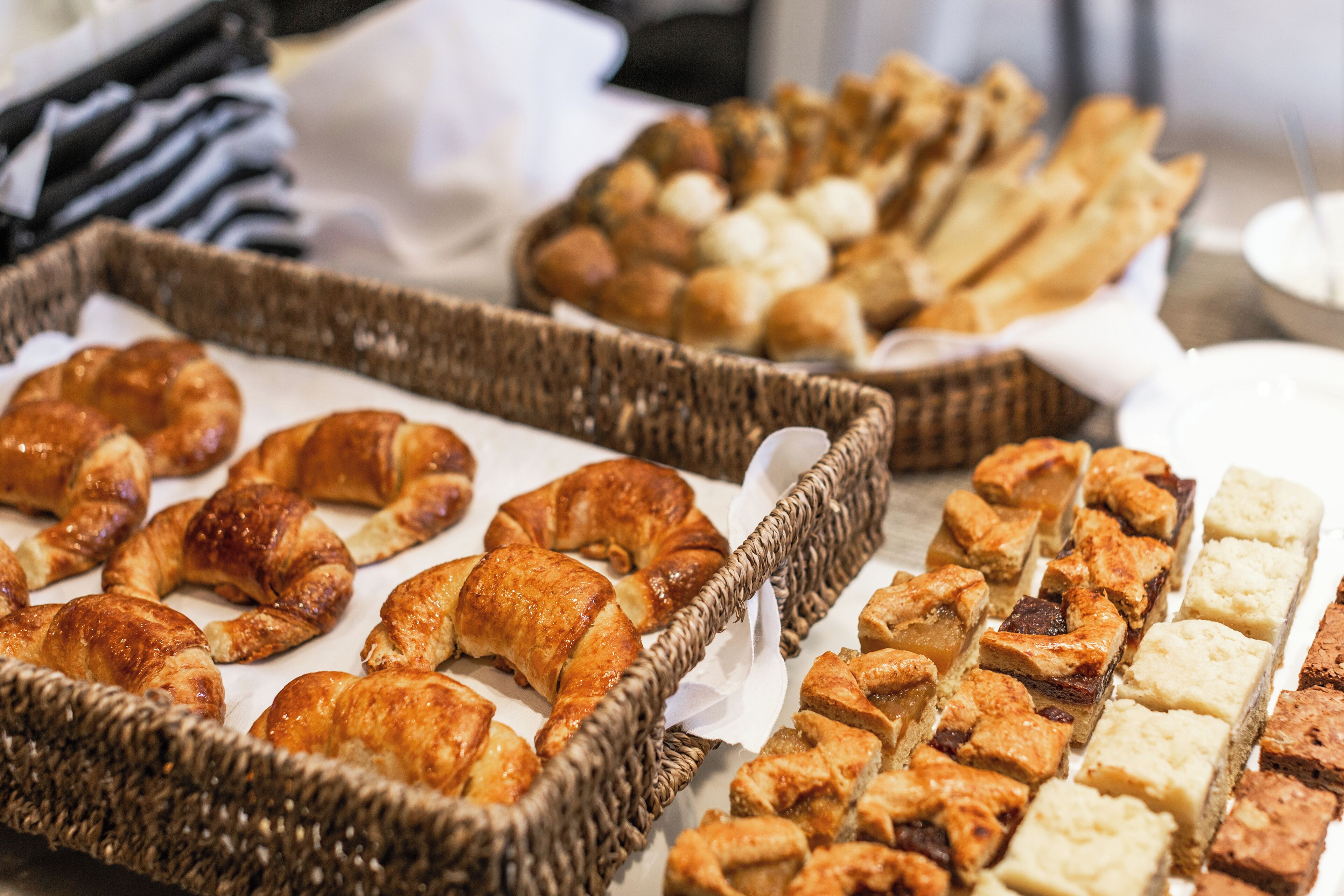 Una variedad de productos de panadería, como croissants y pasteles, dispuesta sobre una mesa.
