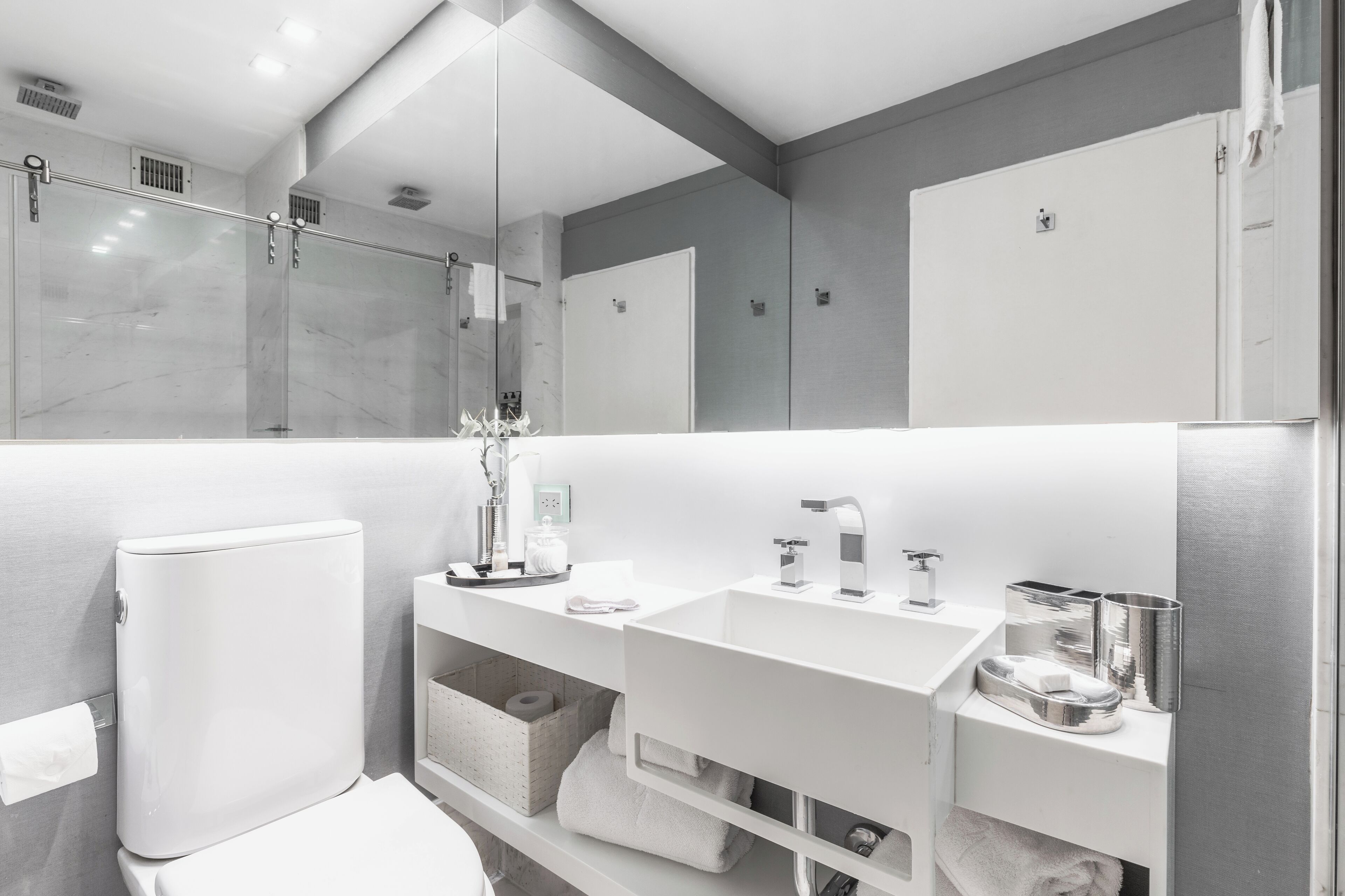 Un bagno moderno con lavandino, specchio e servizi igienici bianchi.