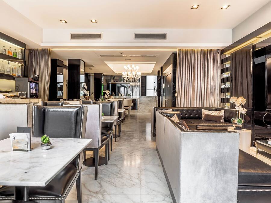 Um lobby de hotel moderno com área de estar central, bar e espaço para refeições.