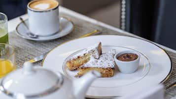 Une table mise pour le petit-déjeuner, avec une assiette de nourriture, une tasse de café et une théière.