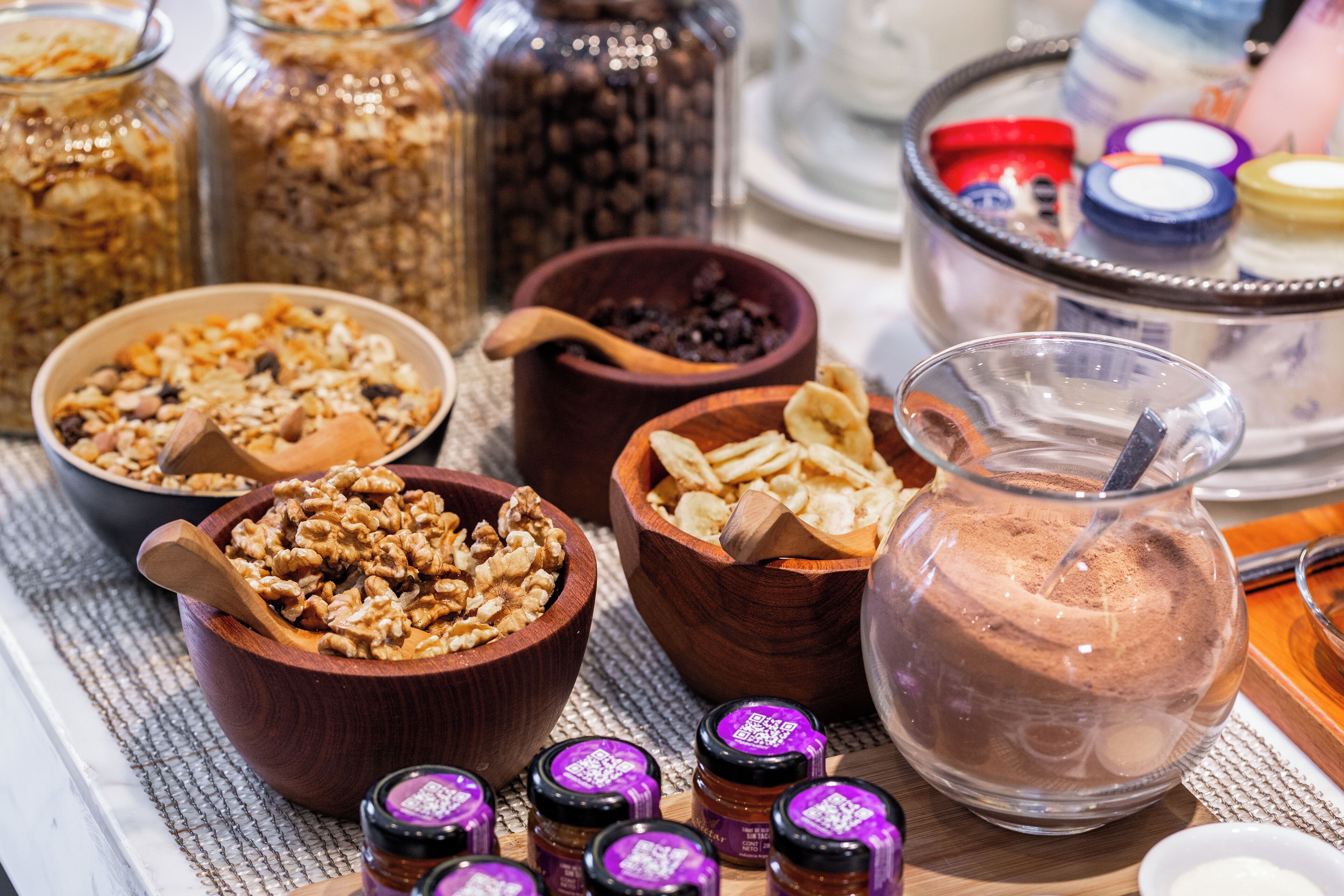 A table with various food items including bowls of granola, nuts, and chocolate mousse.