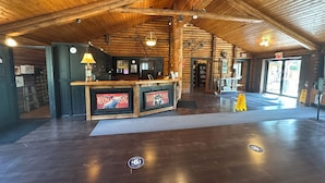 A spacious lobby with a wooden ceiling, a reception desk, and a large window. - Banff Gate Mountain Resort (Canmore)