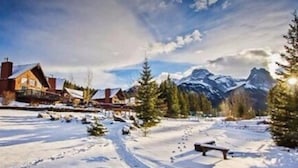 A snow-covered mountain village with traditional wooden houses, a clear sky, and a prominent mountain peak in the background. - Banff Gate Mountain Resort (Canmore)