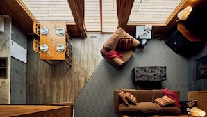 A cozy room with a wooden ceiling, a dining table with plates, a sofa, and a lamp. - Banff Gate Mountain Resort (Canmore)