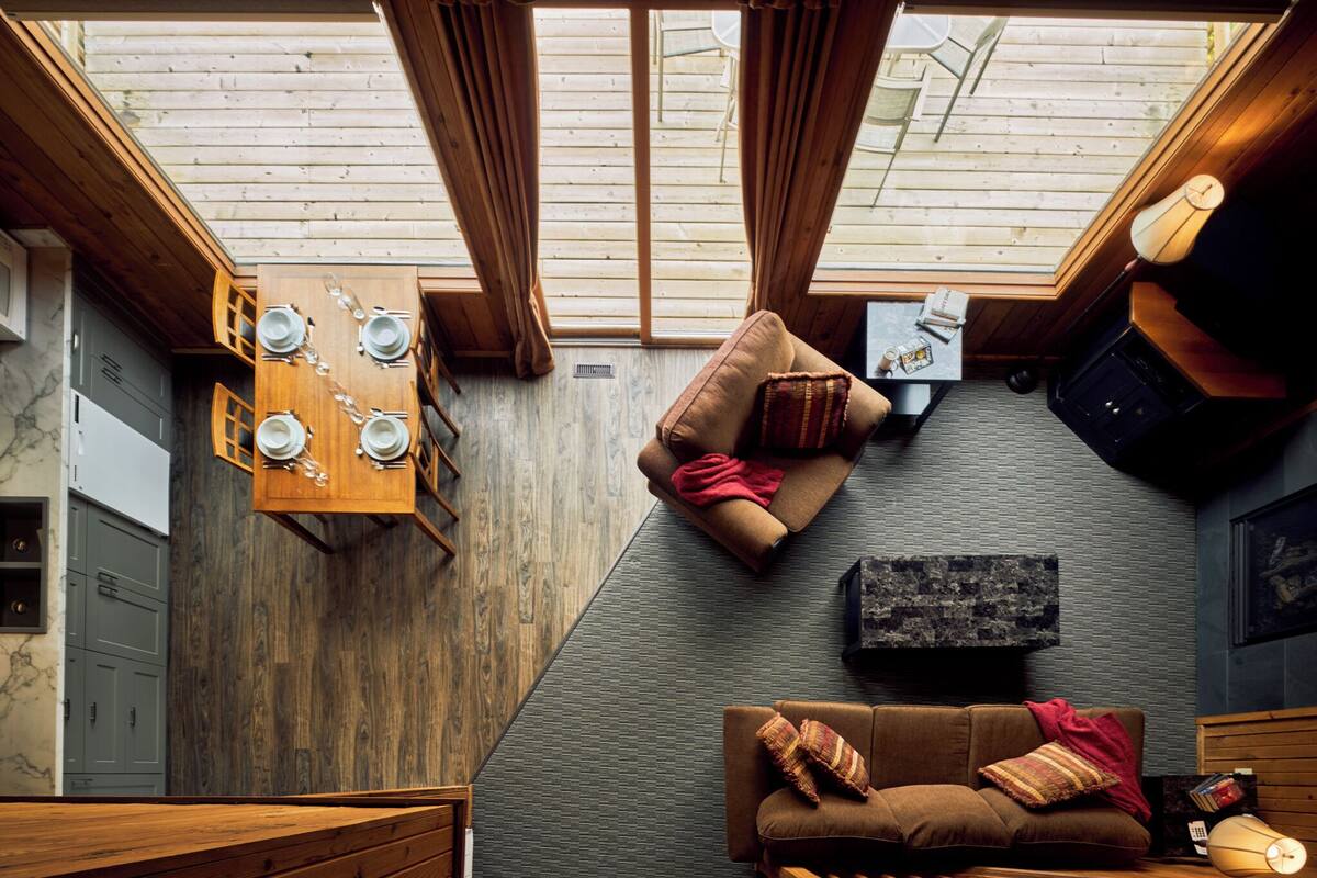 A cozy room with a wooden ceiling, a dining table with plates, a sofa, and a lamp.