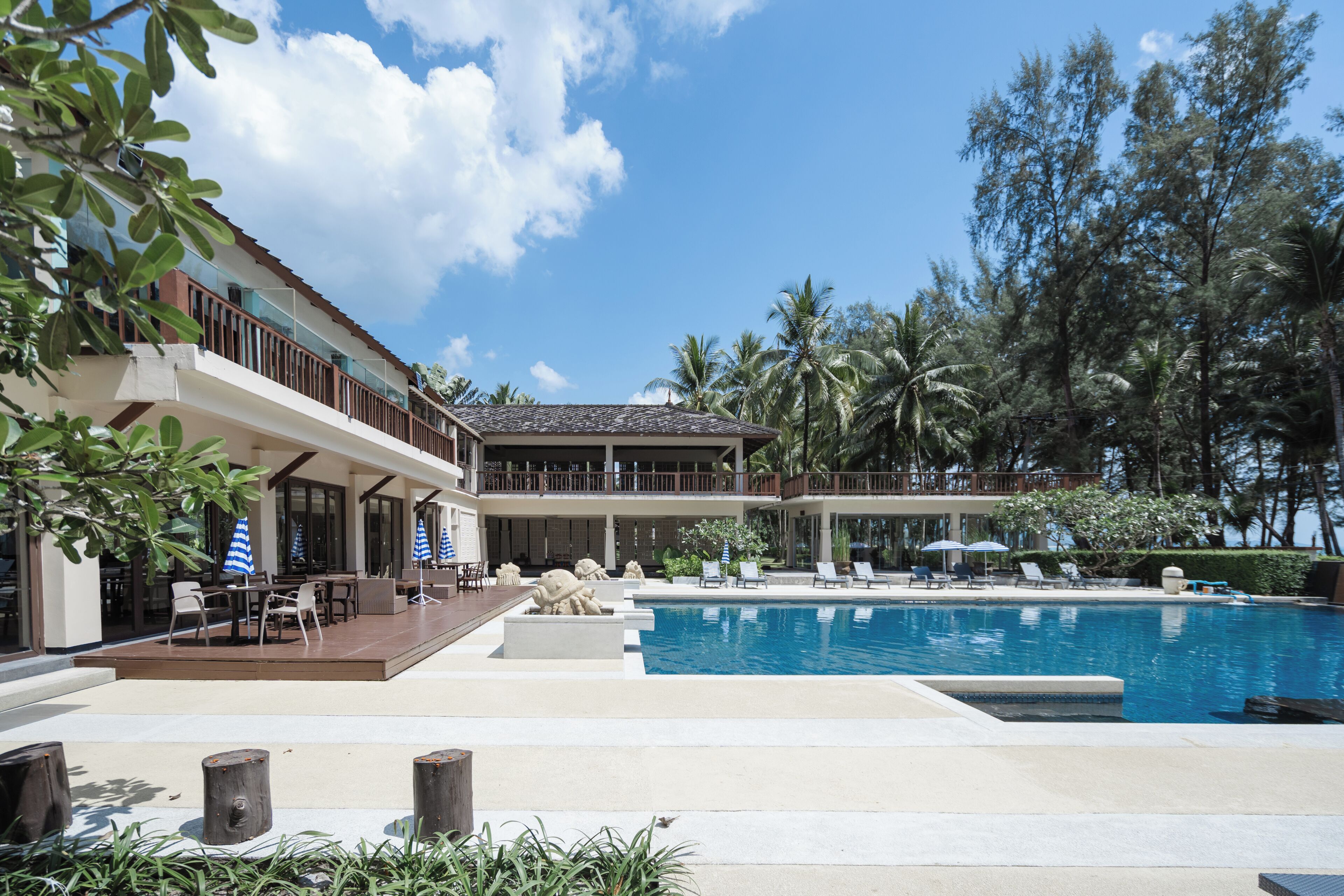 A resort with a swimming pool, outdoor seating, and a covered patio area.