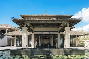Un edificio tradicional con tejado de tejas y un patio central con fuente y plantas de loto.