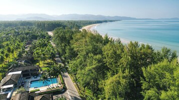 Un resort con piscina, acceso a la playa y un bosque denso.