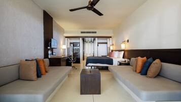 A modern hotel room with a sofa, a bed, a desk, and a ceiling fan.