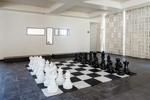 A large indoor space with a checkered floor, chess pieces, and framed pictures on the walls.