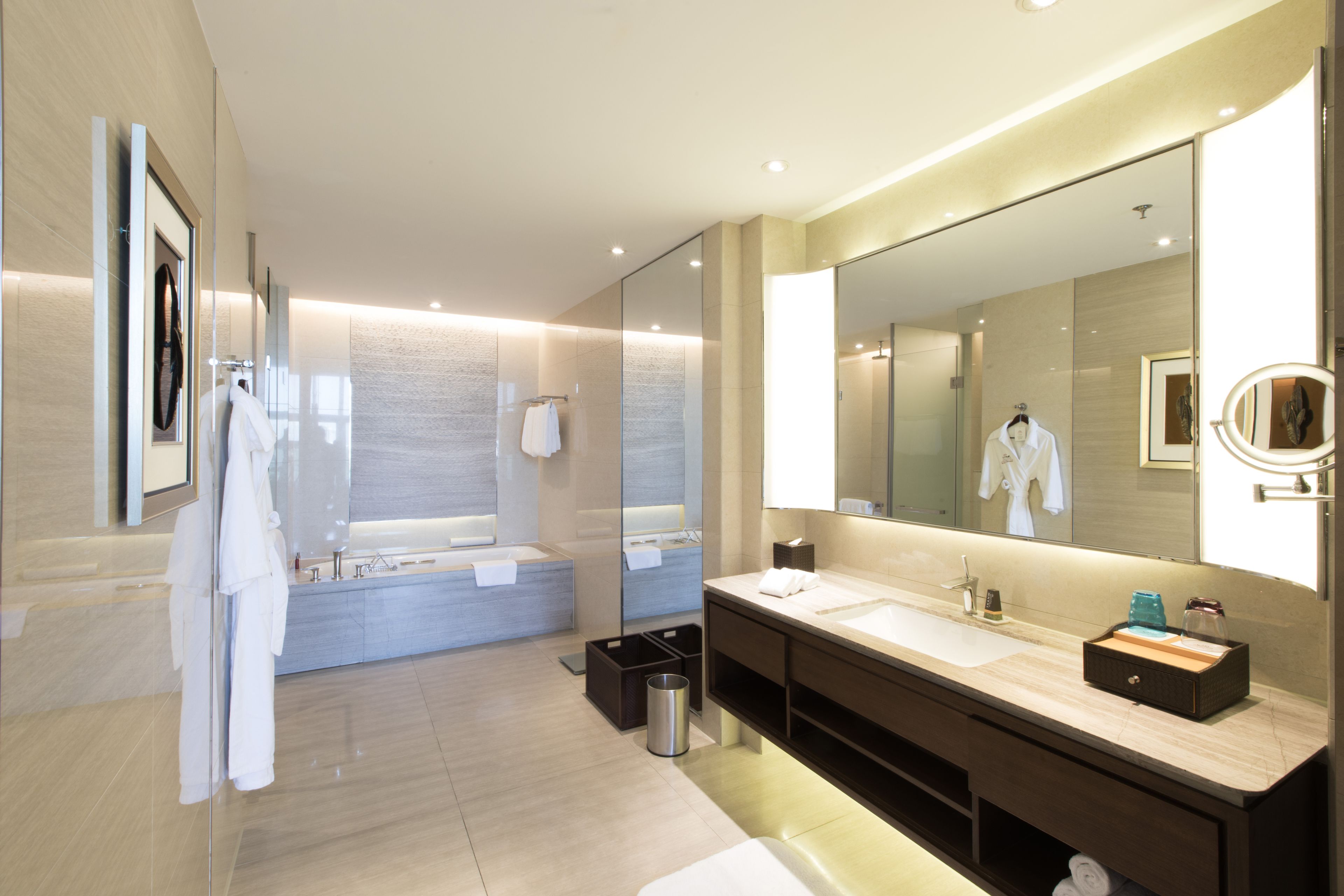 Un baño moderno con un espejo grande, una bañera y un tocador con lavabo.