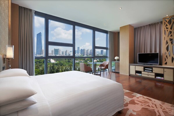 A hotel room with a large bed, a TV, a desk, and a view of the cityscape. - The Oct Harbour, Shenzhen - Marriott Executive Apartments (Shenzhen)