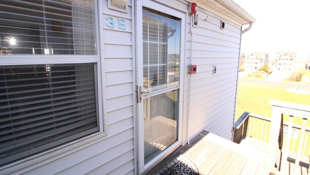 A house with a sliding glass door, a number '3E' sign, and a small deck with a railing.