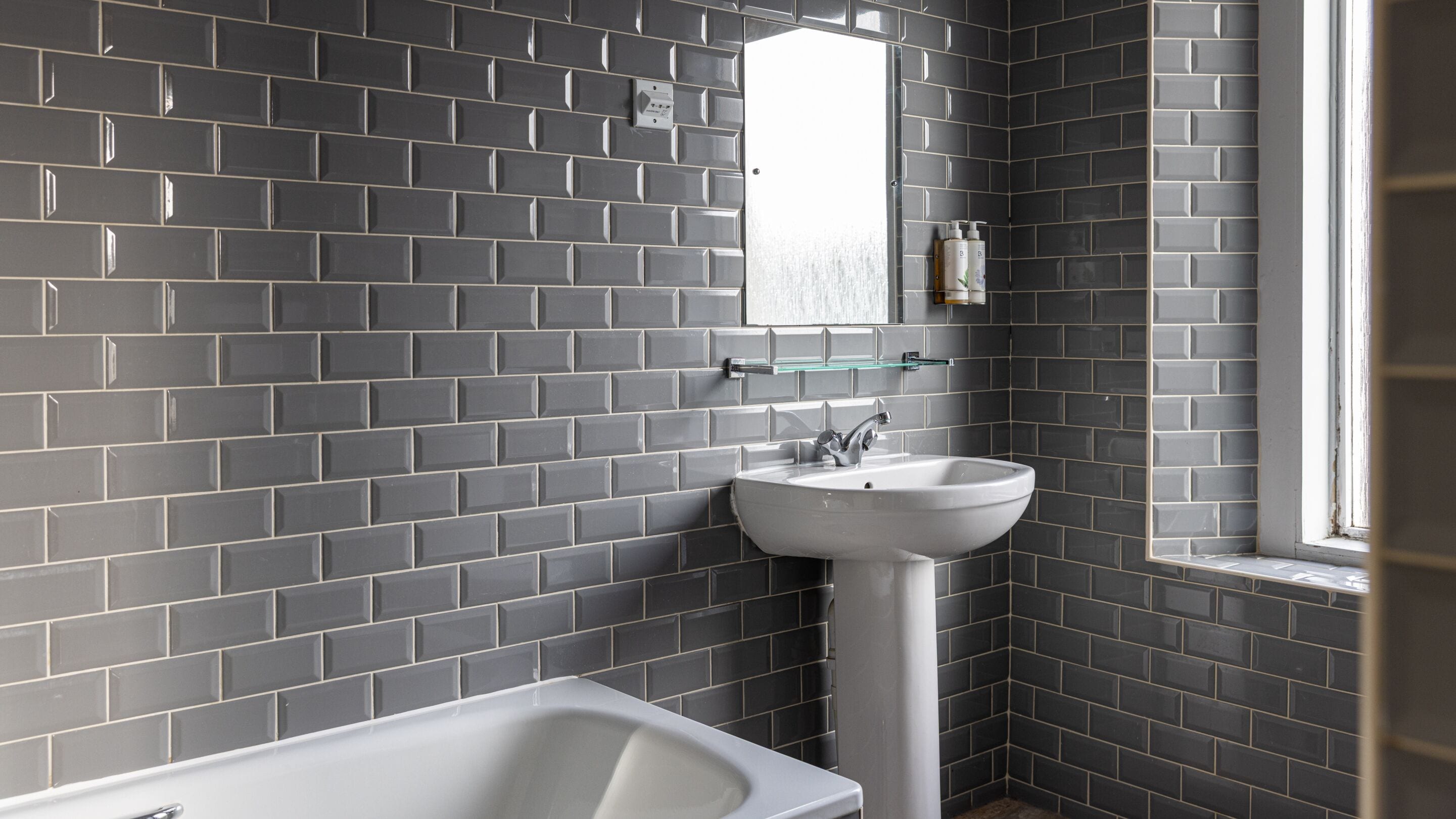 Ein Badezimmer mit einem weißen Waschbecken, einem Spiegel und einer Badewanne.
