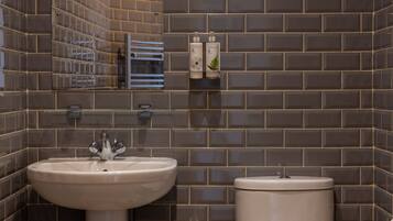 A bathroom with a sink, toilet, and two hand soap dispensers on a shelf.