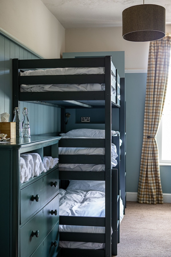 A bunk bed room with a dresser and a lamp.