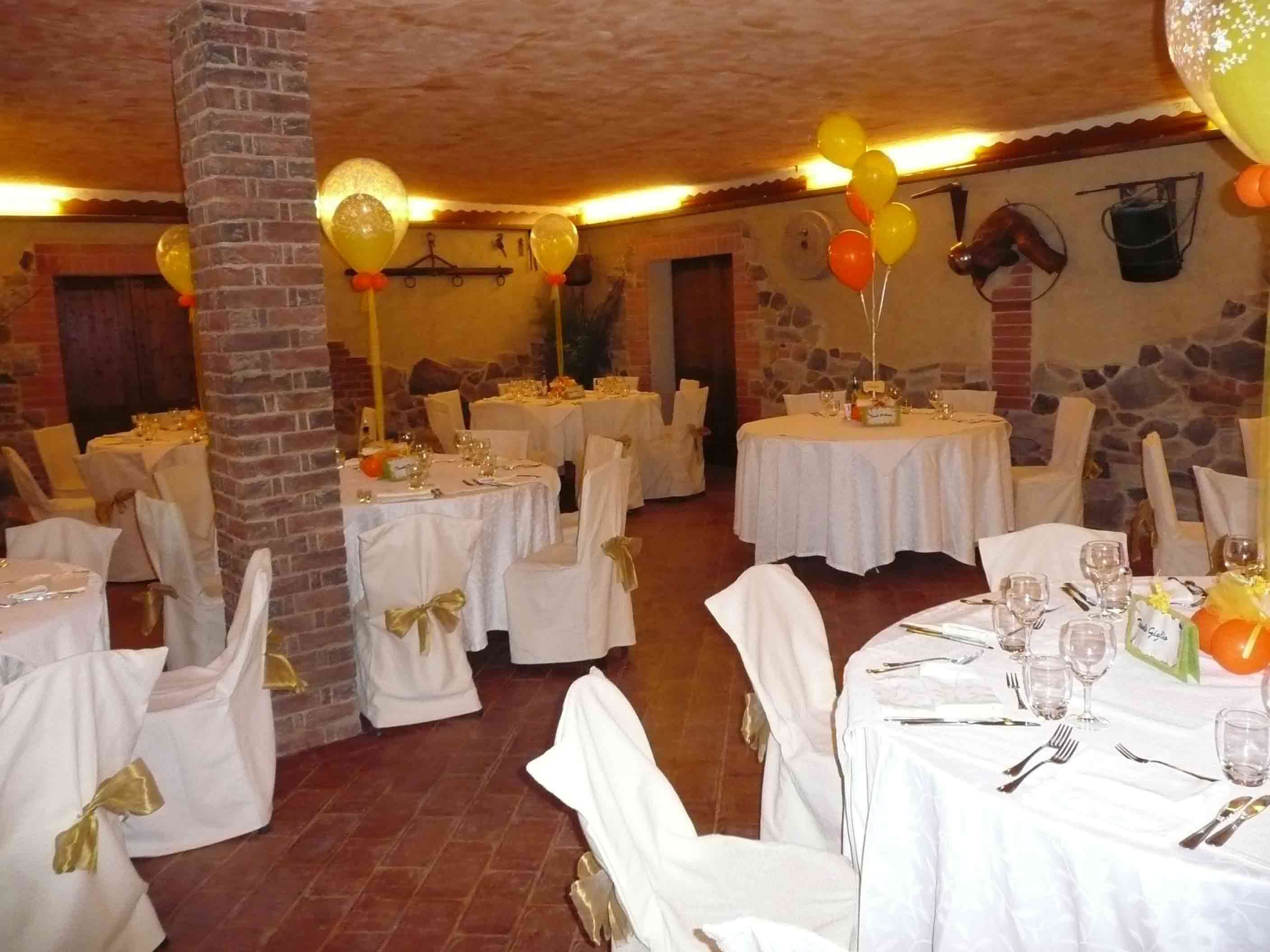 Ein Festsaal mit mehreren runden Tischen, gedeckten weißen Tischdecken und Stühlen mit goldenen Bändern.