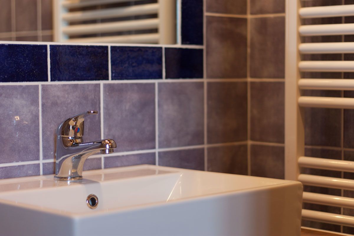 A bathroom with a white sink, chrome faucet, and a tiled backsplash.