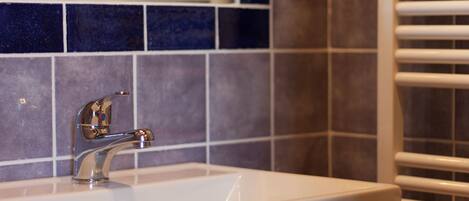 Un baño con lavamanos blanco, grifo cromado y un salpicadero de azulejos.