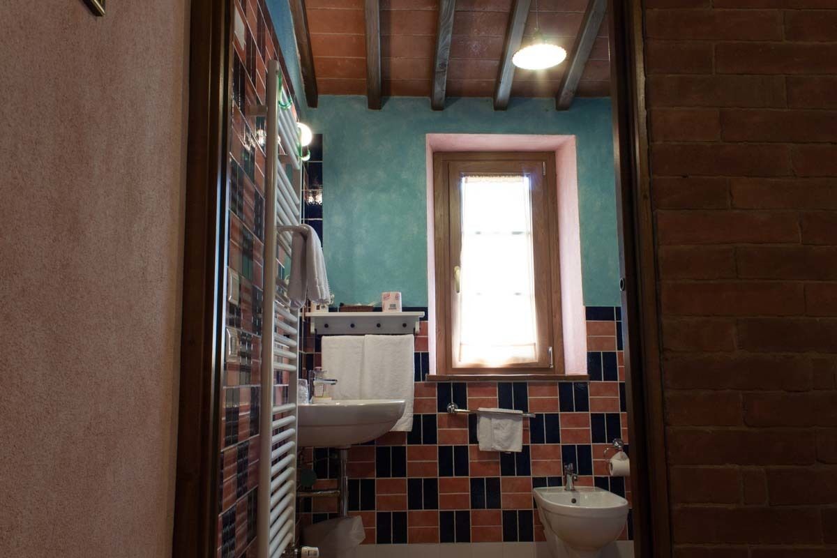 A bathroom with a tiled backsplash, a window, a sink, and a toilet.