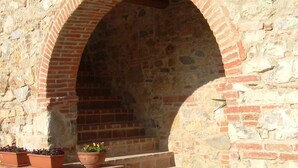 Un arco de piedra que da acceso a una escalera con macetas de terracota a la izquierda.