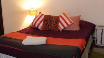 Un dormitorio con una cama, almohadas, un cuadro en la pared y una lámpara.