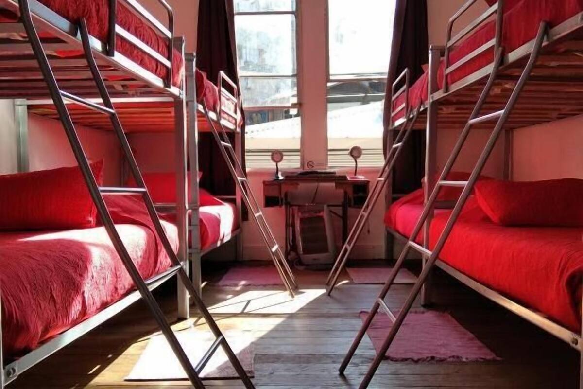 Une chambre de dortoir avec des lits superposés, une petite table et une vue par les fenêtres.