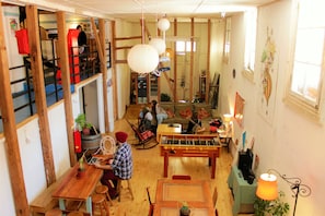 A cozy living room with a foosball table, a sofa, and a person using a laptop.