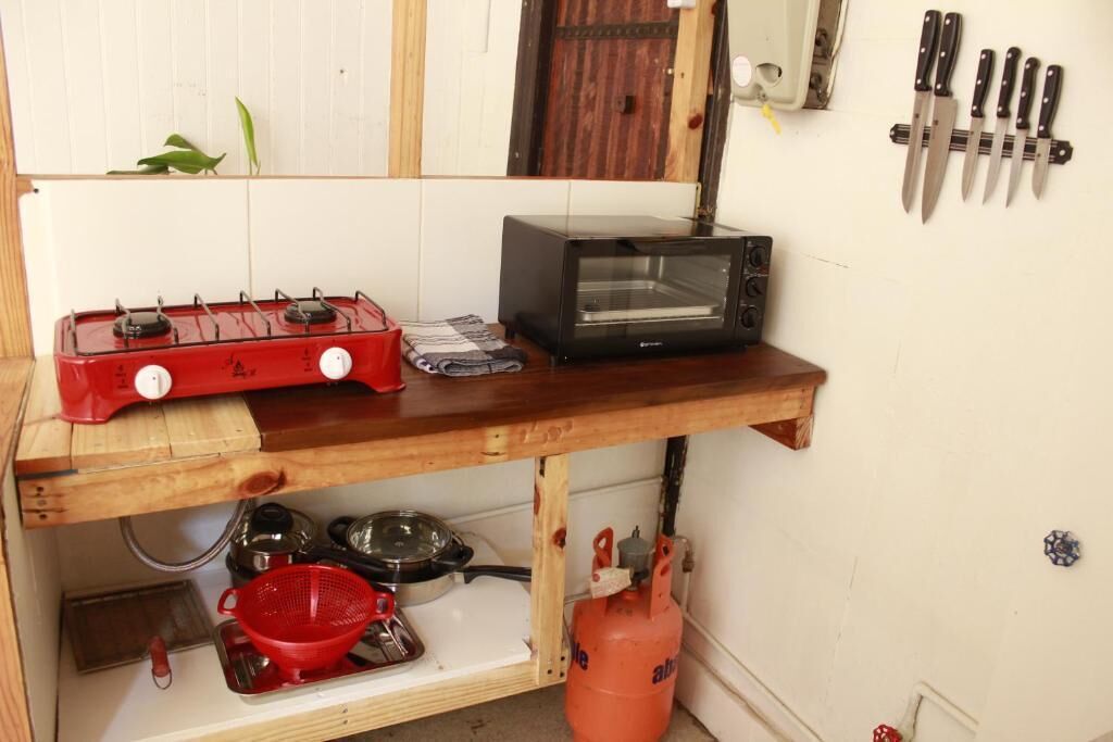 A kitchen with a gas stove, a toaster oven, and a gas cylinder.
