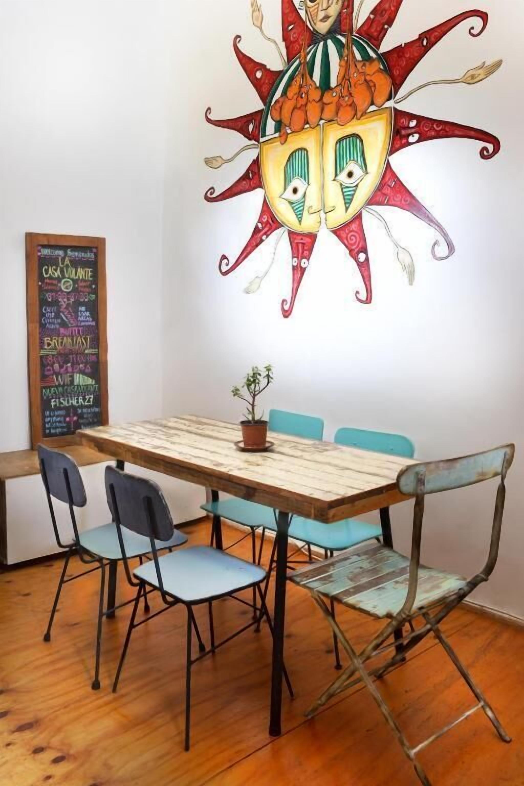 A dining area with a wooden table, four chairs, and a wall mural.