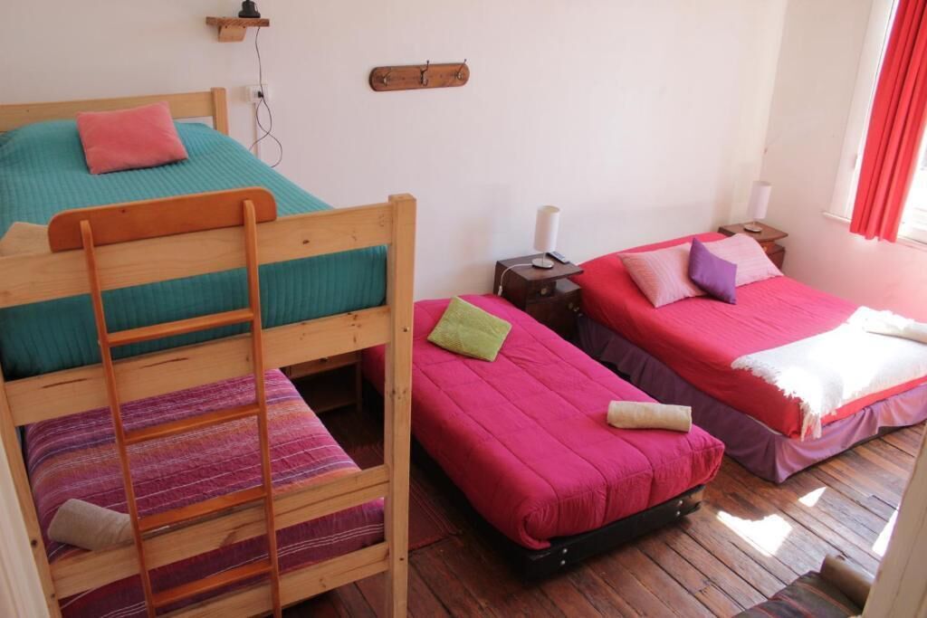 A dormitory-style room with bunk beds, a wooden ladder, and a small bedside table with a lamp.