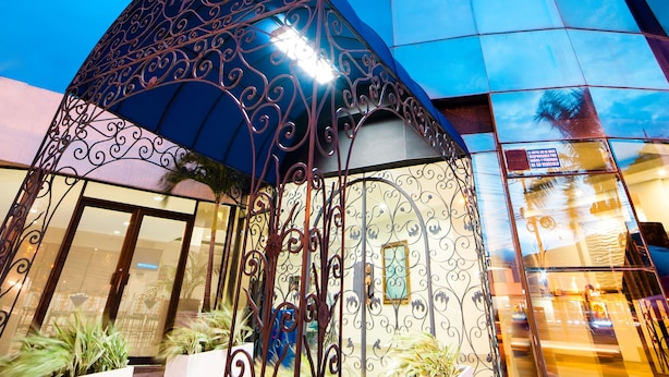 A modern hotel with a curved glass facade, a covered outdoor area with ornate metalwork, and a well-lit entrance. - Hotel Metropolis Plaza (Cali)