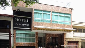 Un hotel llamado 'Hotel Casa Mayor' con una fachada moderna, ventanas amplias y una entrada visible con escalones que conducen a la puerta principal.